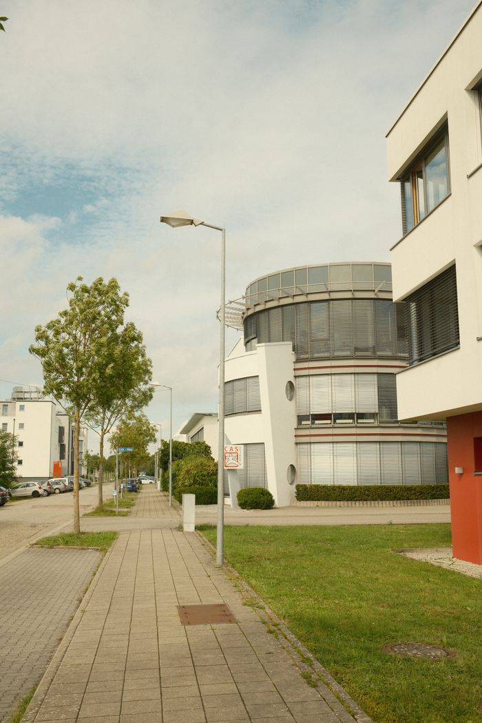 Street view of modern architecture and buildings with green space under a blue sky.